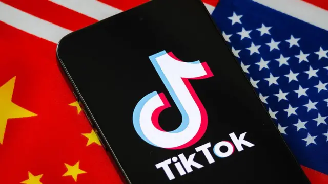 En esta ilustración, un teléfono inteligente muestra el logotipo de TikTok con las banderas nacionales de China y Estados Unidos en el fondo.