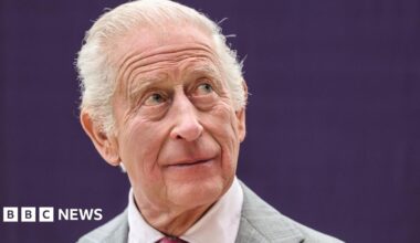 King Charles III during his visit to officially open the new Midland Metropolitan University Hospital in Birmingham. He has short grey hair and is wearing a grey suit.