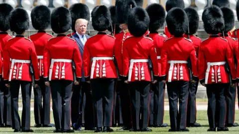 Getty Images Wearing a blue suit and pale blue tie, Donald Trump inspects a Guard of Honour formed by red-coated Grenadier Guards at Buckingham Palace during his state visit to the UK in June 2019. 