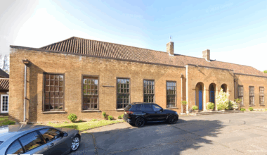 We can see the front of Jaguar House, a 1930s single-storey RAF building. It has large windows and three arches in front of its main entrance.