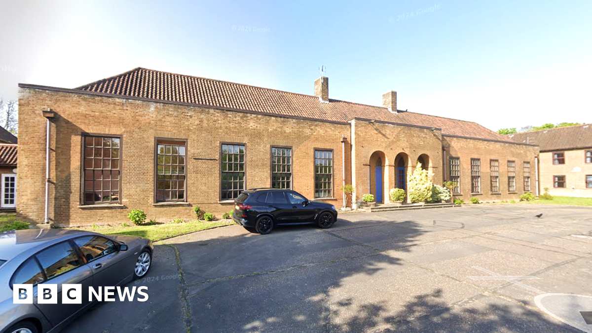 We can see the front of Jaguar House, a 1930s single-storey RAF building. It has large windows and three arches in front of its main entrance.