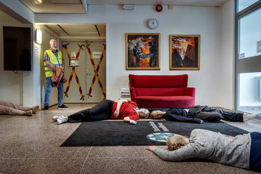 Elever från Norra Real har sminkats simulera olika skador, syftet är att träna upp motståndskraften mot en potentiell skolattack. En representant från kommunen i gul väst följer övningen.