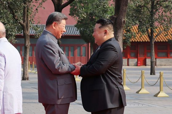 North Korean leader Kim Jong-un, right, holds hands in greeting with Chinese President Xi Jinping before the Victory Day parade in Beijing on Sept. 3. [NEWS1]
