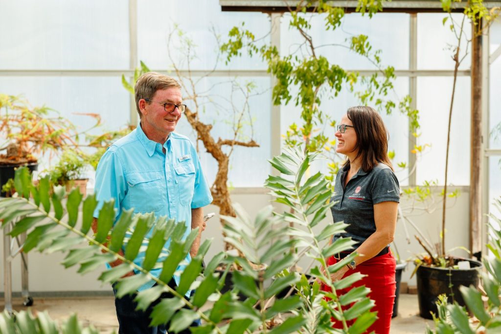 two people talking in a greenhouse
