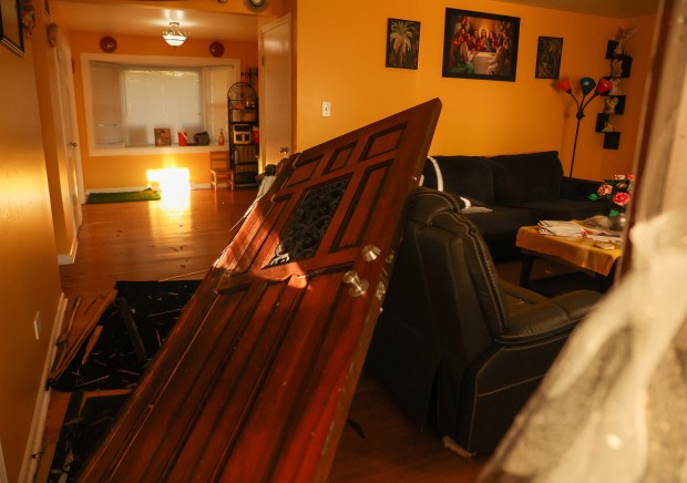 The front door of a home along the 900 block of Chippewa Drive is torn from its hinges and lies on a sofa after federal agents broke it down in the early morning on Sept. 16, 2025, in Elgin. (Stacey Wescott/Chicago Tribune)