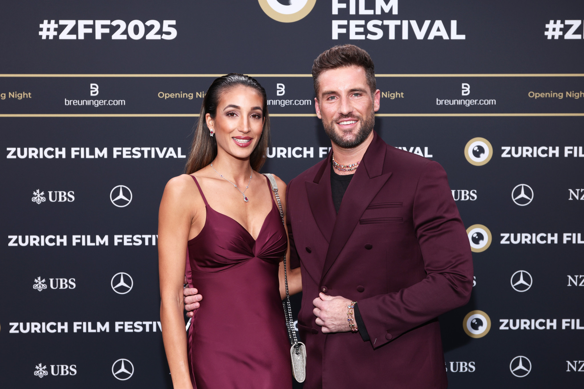 Sara Leutenegger und Steven Epprecht posieren auf dem grünen Teppich des Zurich Film Festival 2025 in eleganter Abendgarderobe.