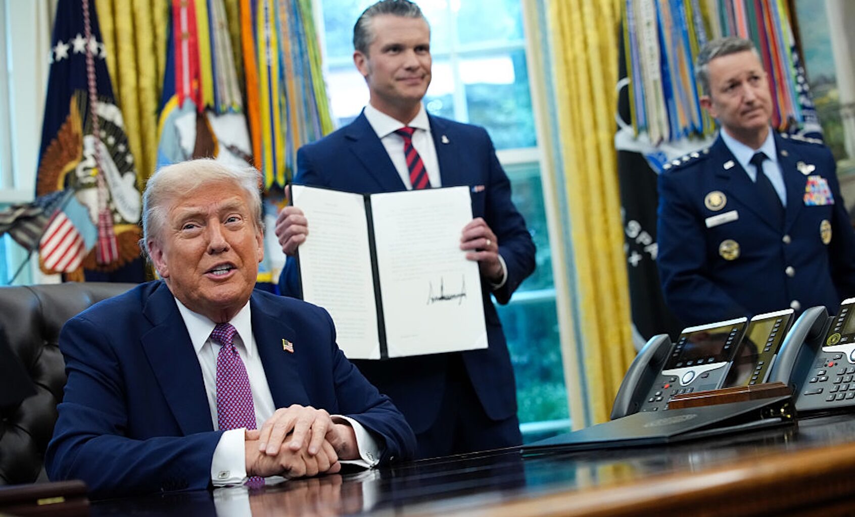 President Donald Trump speaks to the media after signing an executive order renaming the Department of Defense the Department of War as Defense Secretary Pete Hegseth and Chairman of the Joint Chiefs of Staff Air Force Gen. Dan Caine (R) look on in the Oval Office on Sept. 5, 2025. (Kevin Dietsch/Getty Images)