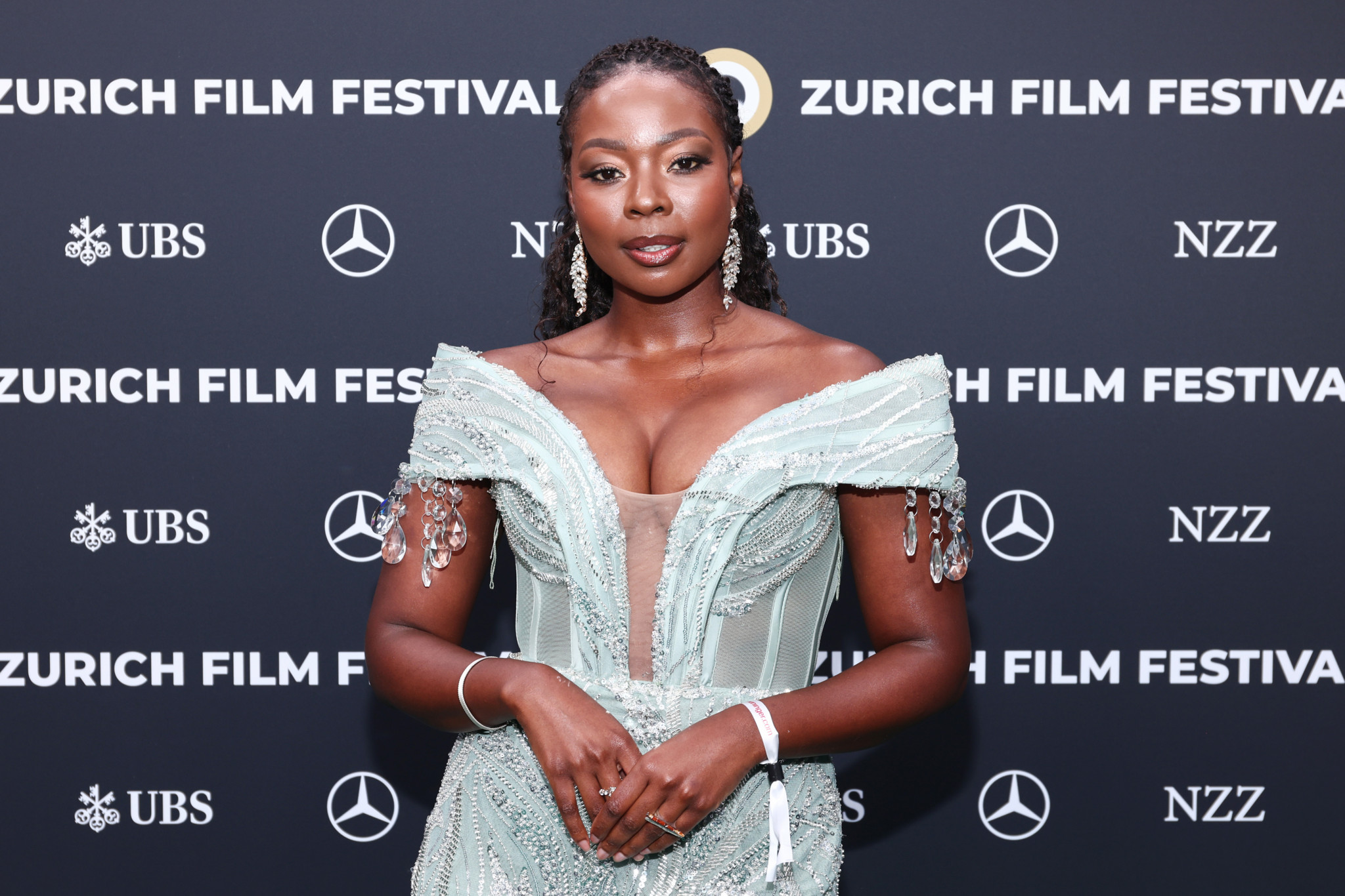 Nambitha Ben-Mazwi auf dem grünen Teppich des Zurich Film Festivals 2025 in einem eleganten, schulterfreien Kleid vor Sponsorenwand.
