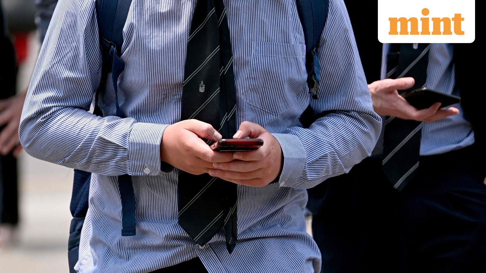 A file photo of youngsters looking at their phones in Melbourne as Australia. Tech companies including WhatsApp and Reddit as well as streaming giant Twitch and gaming firm Roblox could be among more than a dozen sites added to Australia's social media ban for under-16s, the country's regulator said on September 24, 2025.