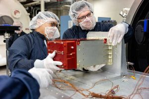 Engineering technologist Adolfo Salazar, left, and systems engineer Sean Walker prepare a sensor from the IIIF Global Burst Detector for thermal vacuum testing. (Photo by Bret Latter) Click on the thumbnail for a high-resolution image.