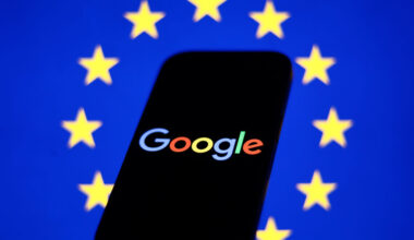 European Union flag displayed on a laptop screen and Google logo displayed on a phone in front of it