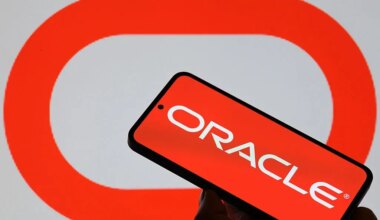 The Oracle logo is displayed on a mobile phone with the company's branding seen in the background in this photo illustration.