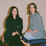 Two women seated on a gallery floor.