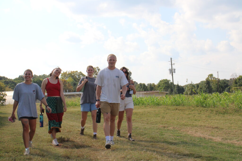 Owen Setterlind walks with his friends through a field to go to their UGArden meeting.