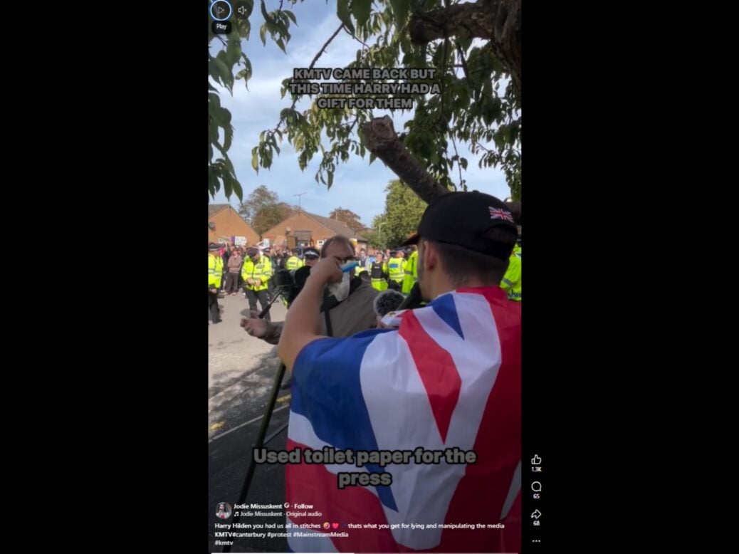 A screenshot of a Facebook video, showing a protester holding up a bag of 'used toilet paper' in Ollie Leader's face