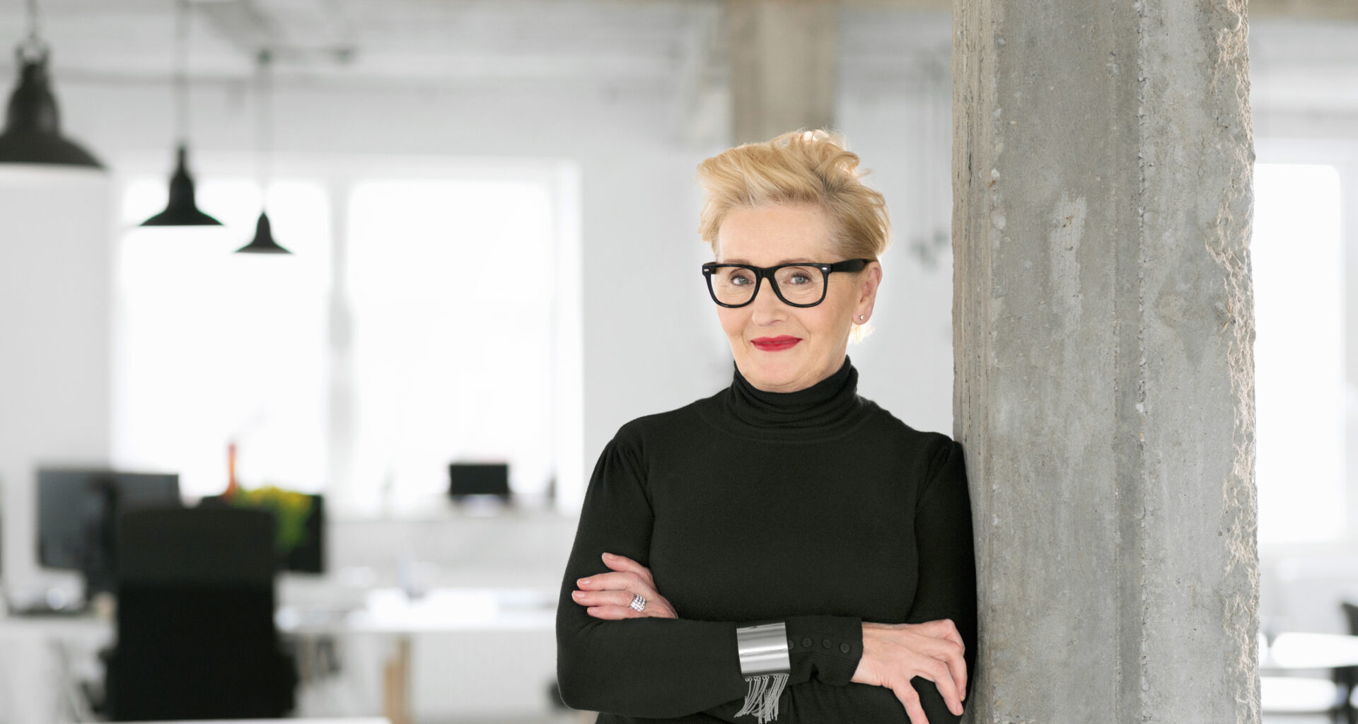 Portrait of elegant older businesswoman standing in the modern studio, smiling at the camera.