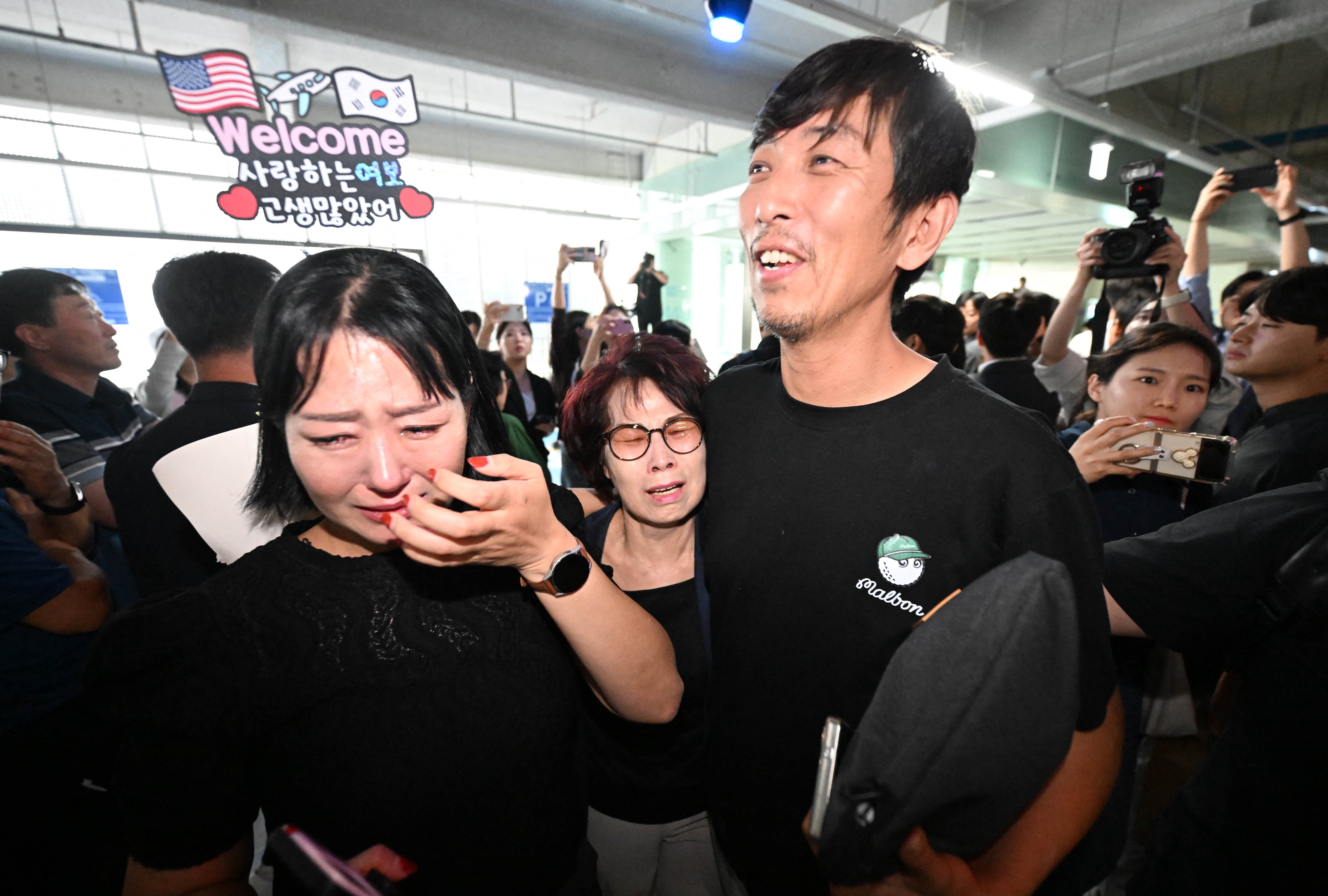A South Korean worker (R), who was detained in a US immigration raid at a Hyundai-LG plant in Ellabell, Georgia, is welcomed by family members after returning from Atlanta at a parking lot in Incheon International Airport