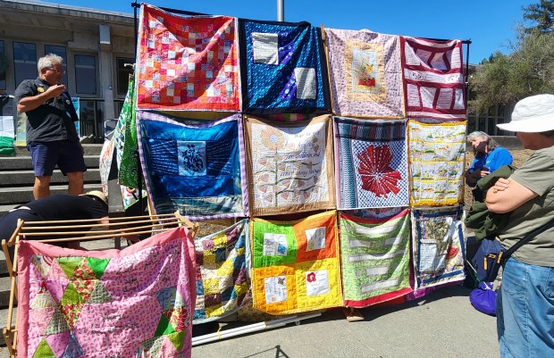 Community members admire the quilts made by local artists that...