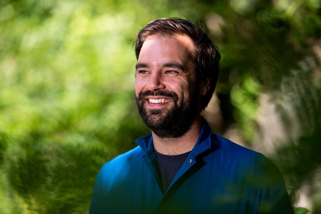 Portrait of Samuel Munoz wearing a blue shirt in front of a green background. 