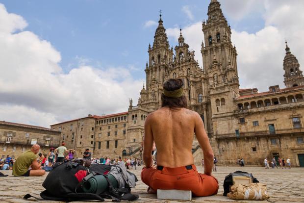 Pilgrims and tourists rest in front of the cathedral in Santiago de Compostela, northwestern Spain, Thursday, Aug. 21, 2025. (AP Photo/Lalo Villar)