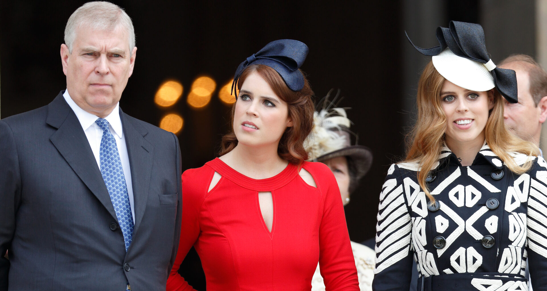 Princess Eugenie wears a bright red dress and a black ribbon on her head, while her sister Princess Beatrice wears a black and white patterned dress with a white hat featuring a black bow