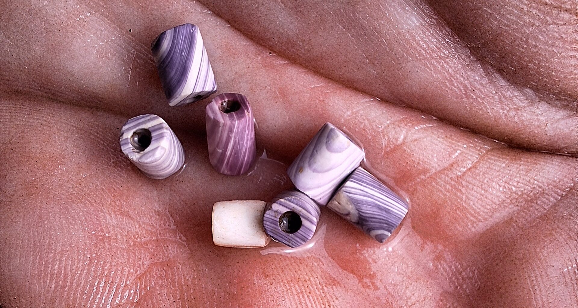 A collection of purple and white marbled beads in the palm of a hand
