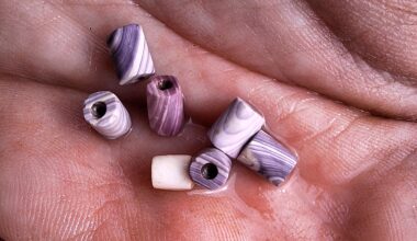 A collection of purple and white marbled beads in the palm of a hand