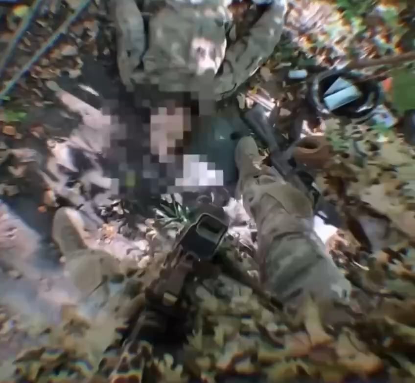 A Ukrainian soldier in a leaf suit collected a patch from an eliminated Russian soldier that says "Victory will be ours"