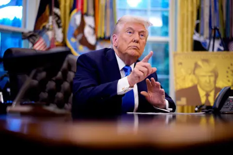 Getty Images President Donald Trump takes a question from a reporter before signing executive orders in the Oval Office at the White House on September 19, 2025 in Washington, DC. Trump signed two executive orders, establishing the "Trump Gold Card" and introducing a $100,000 fee for H-1B visas. 