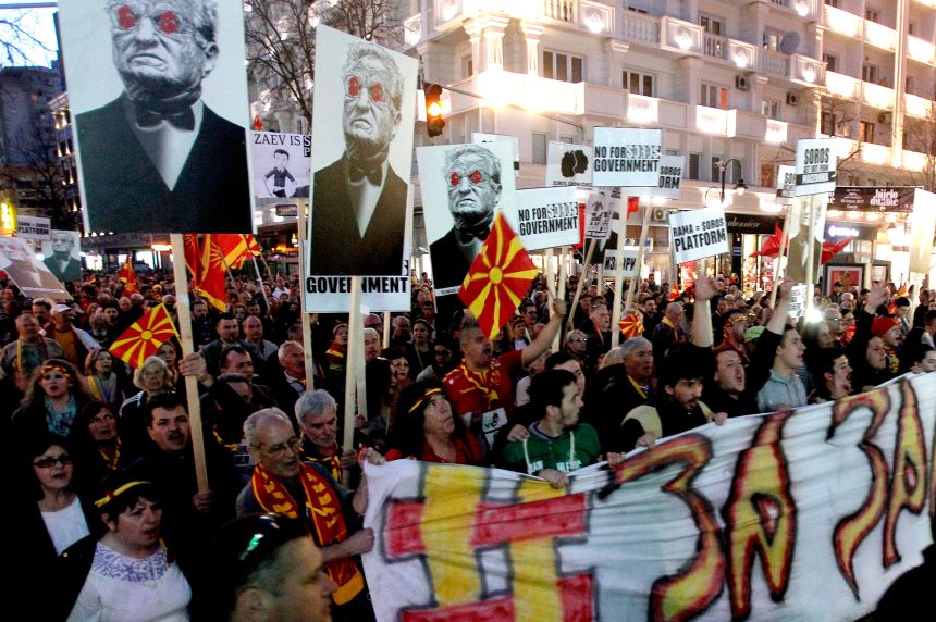Protesters carry posters featuring George Soros and banners reading 