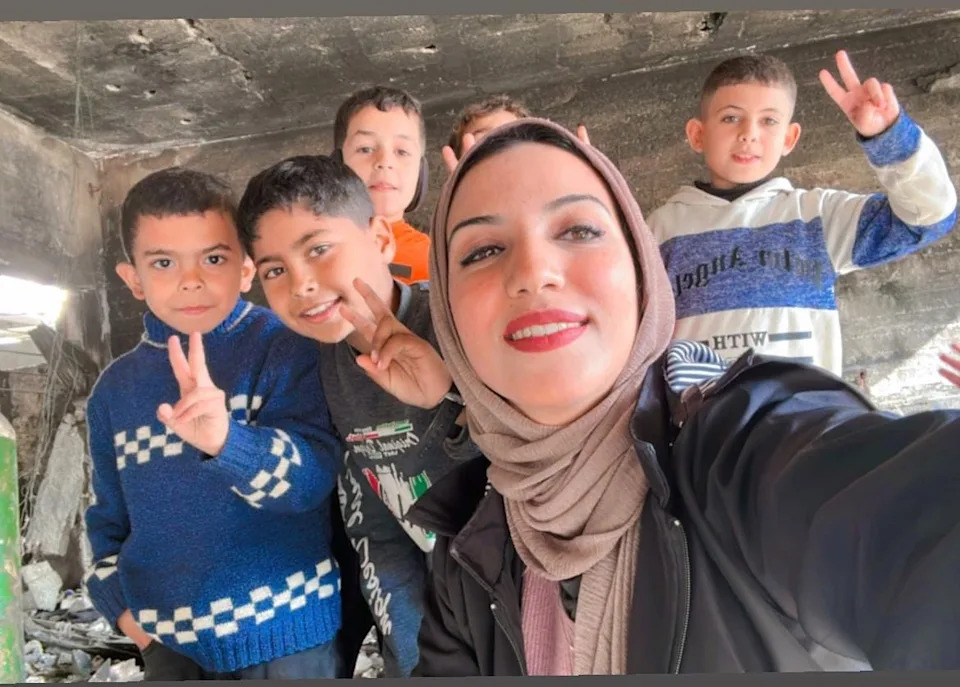 Farida Al-Ghoul, a writer and educator sheltering in northern Gaza, poses with her younger siblings.