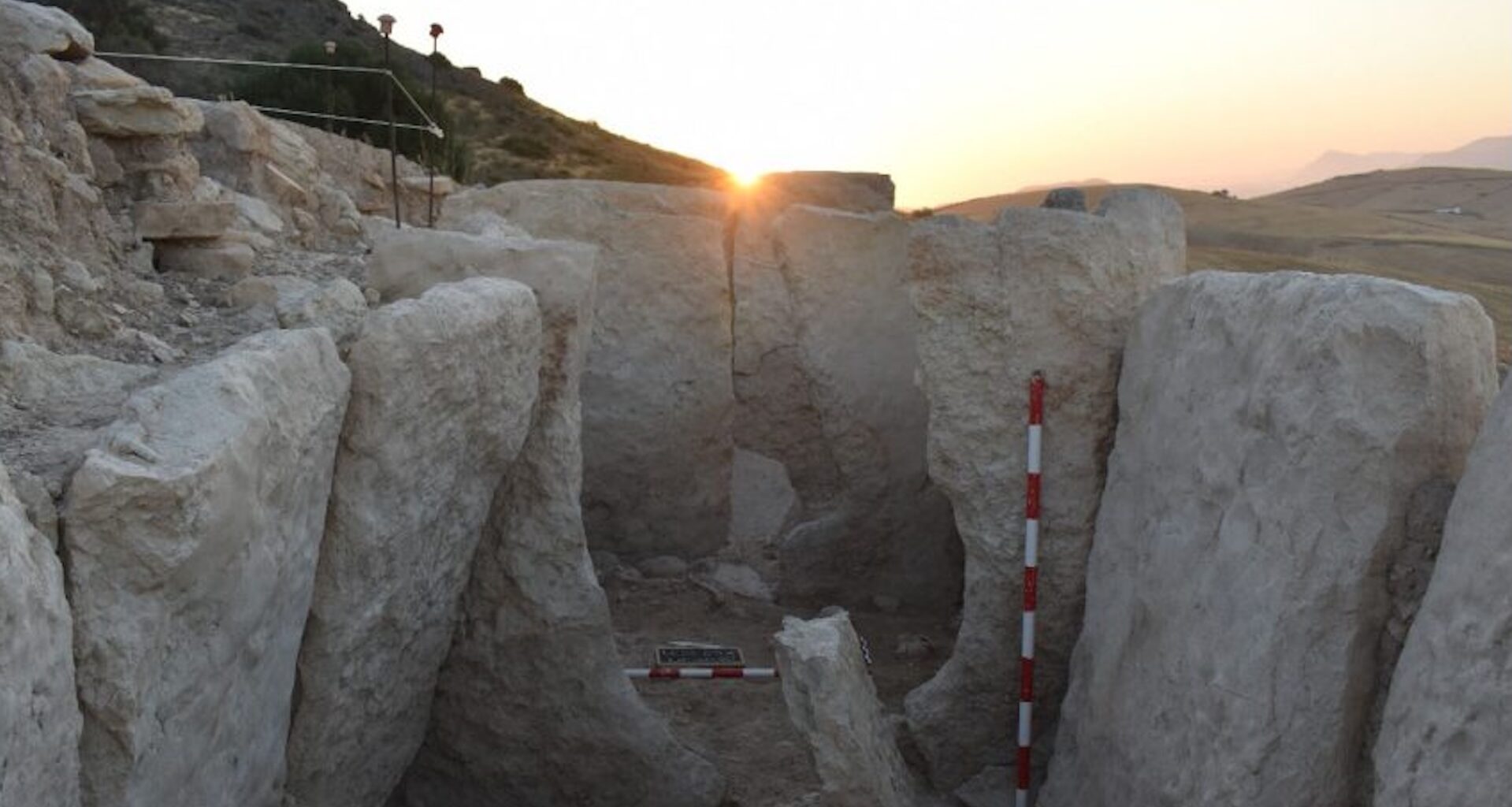 a photo of a massive rock structure at sunset