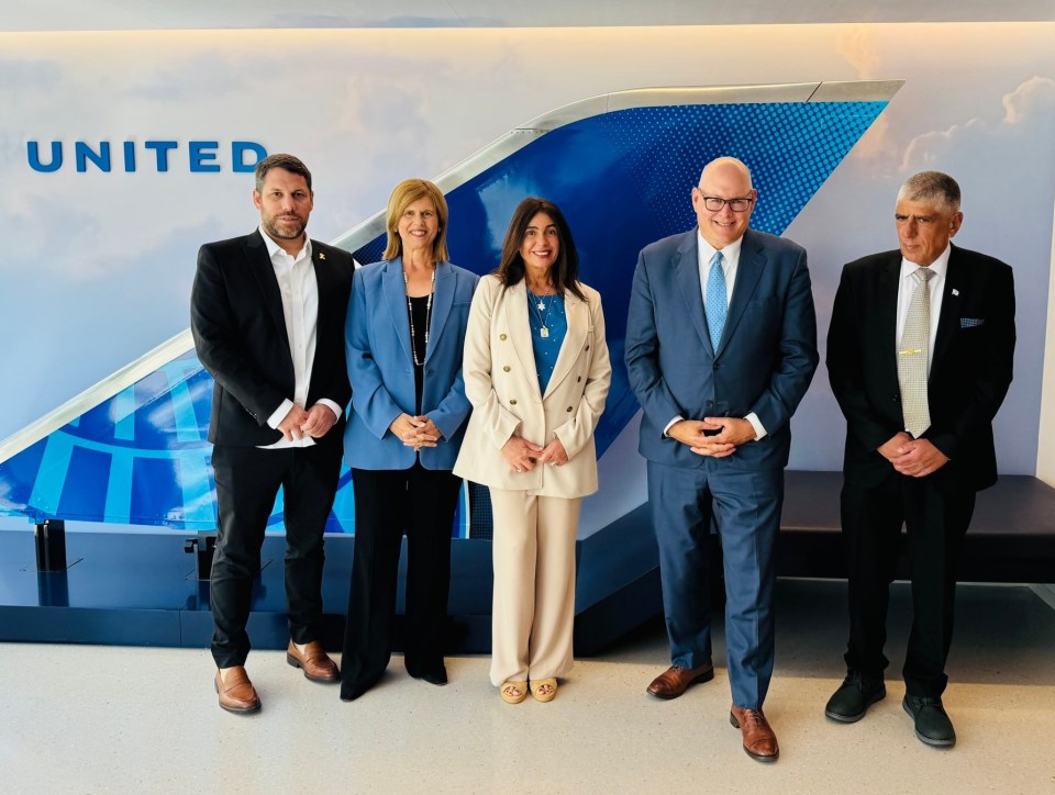 Five people stand in front of a United Airlines display.