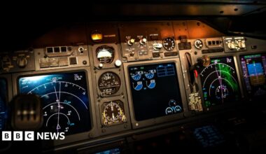 Stock image of an airplane cockpit's navigation systems at night. Shown is several screens and dials, as well as controls.