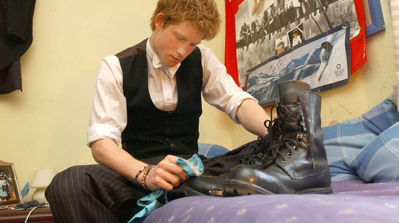 Prince Harry sits in his room as he polishes boots.
