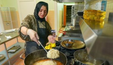 Breshna Alemi ladles rice into simmering oil and onions to make Qabeli rice for a catering order. She's part of anentrepreneurship program Chef's Club, which helps refugee women start their own food businesses.