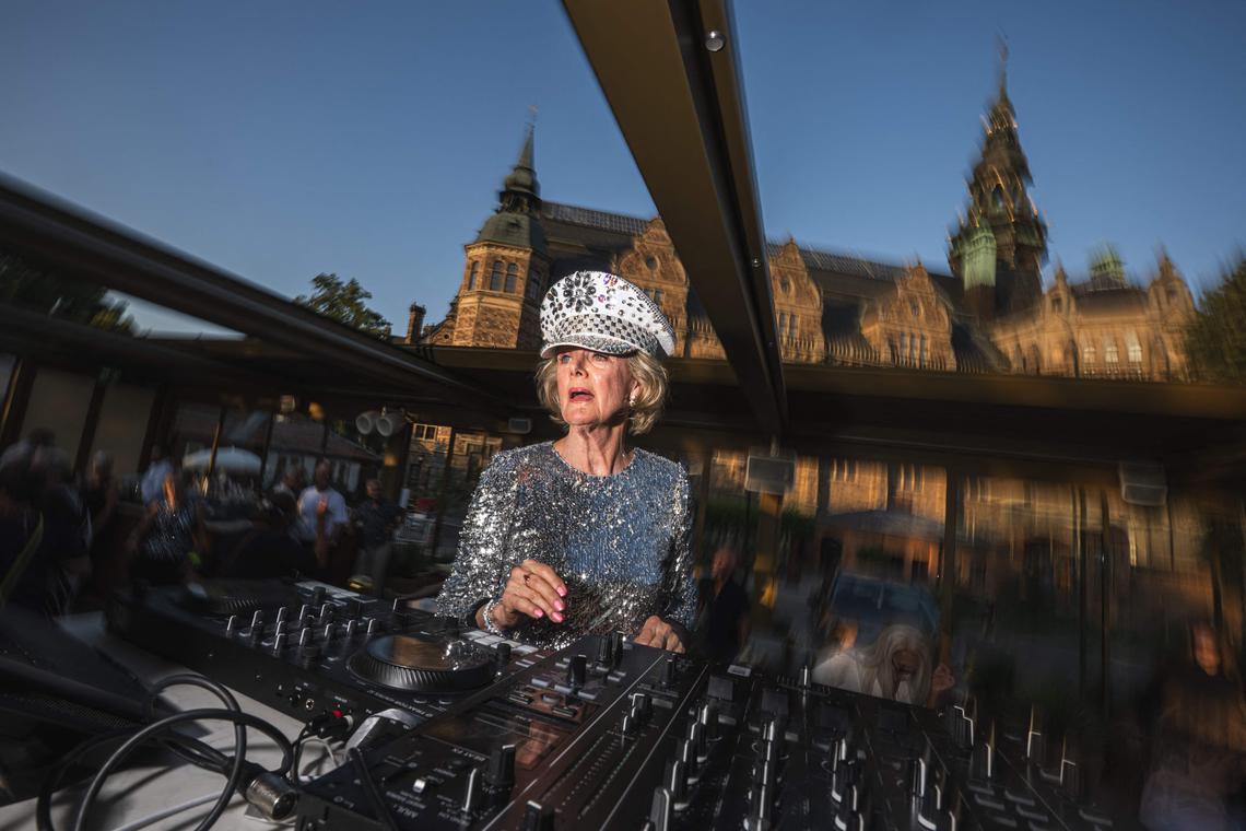 81-year-old Madelein Mansson, aka “DJ Gloria”, performs at Josefina, an outdoor summer bar and club in Stockholm, Sweden, on July 18, 2025. She drops the beat and gets her groove on, spinning discs like a pro as her head-to-toe sequins twinkle under the lights: at age 81, DJ Gloria is filling dancefloors across Sweden. (Photo by Jonathan NACKSTRAND / AFP) / TO GO WITH AFP STORY BY PIA OHLIN