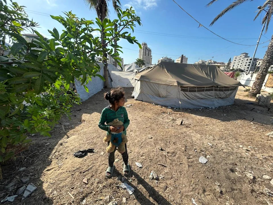 A child stands outside the tent where Farida Al-Ghoul, a writer and educator sheltering in northern Gaza, has been living with her younger siblings.