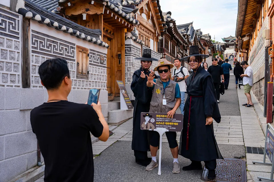 Men dressed as the Saja Boys take a picture with a local safety guard in Bukchon Hanok Village in Seoul on Tuesday. - (Jintak Han/The Washington Post)