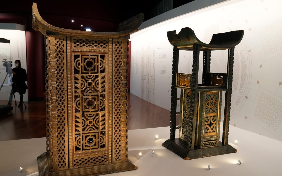Two wooden structures with gold designs on them are shown inside an exhibit.