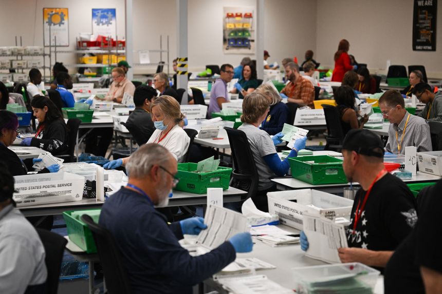 Election workers open and inspect mail-in ballot envelopes after they completed signature verification inside the Maricopa County Tabulation and Election Center in Phoenix, Arizona, on November 5, 2024.