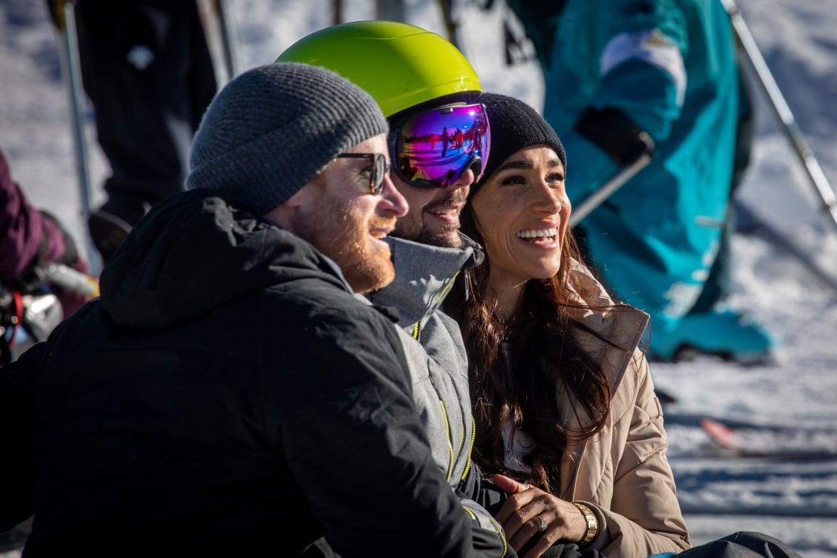 Three people wearing winter gear look off to the right.