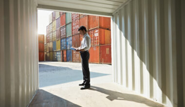 Man standing in the entrance of a shipping container with other containers in the background