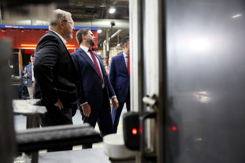 Vice President JD Vance stands next to someone with goggles at Hatch Stamping company in Howell, Michigan.