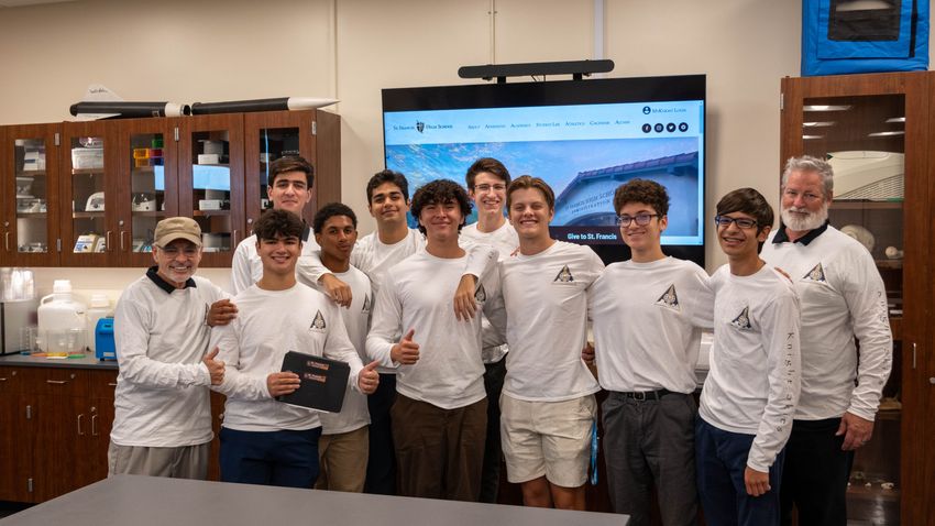 Photo [Inline image alt text]: Image of 11 people standing in a row. All of them wear matching white long sleeve shirts with the Knight Skies Program logo on the chest.
