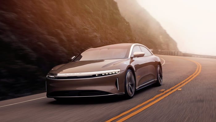 An all-electric Lucid Air sedan driving on a windy mountain road. 