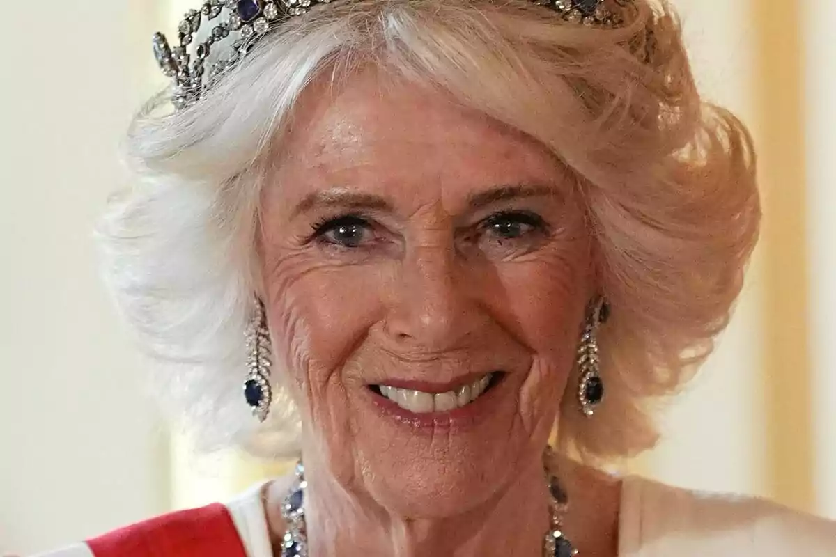 Blonde, short-haired woman with a crown and jewelry smiles at the camera