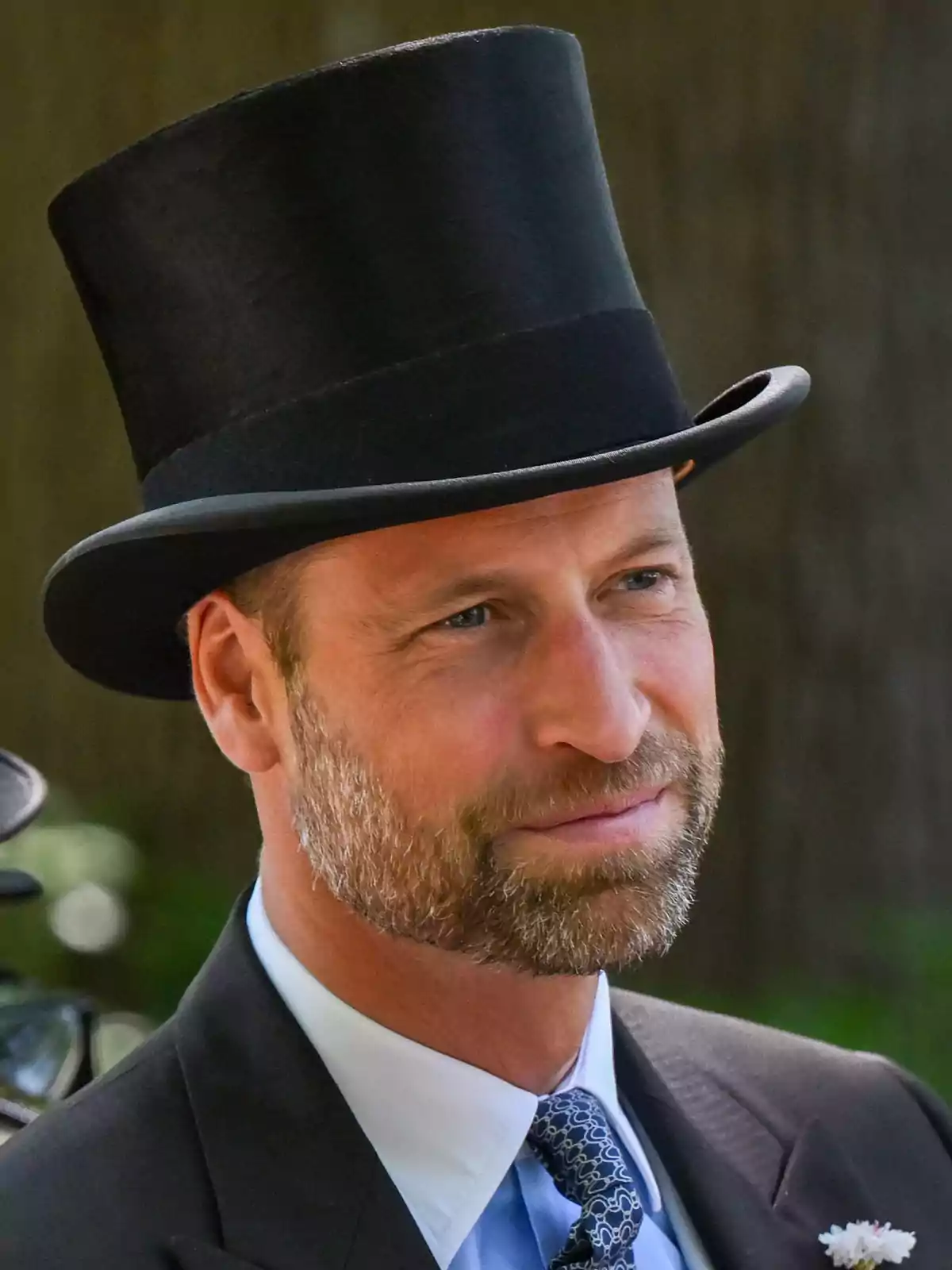 Prince William wearing a top hat, formal suit, and tie at an outdoor event