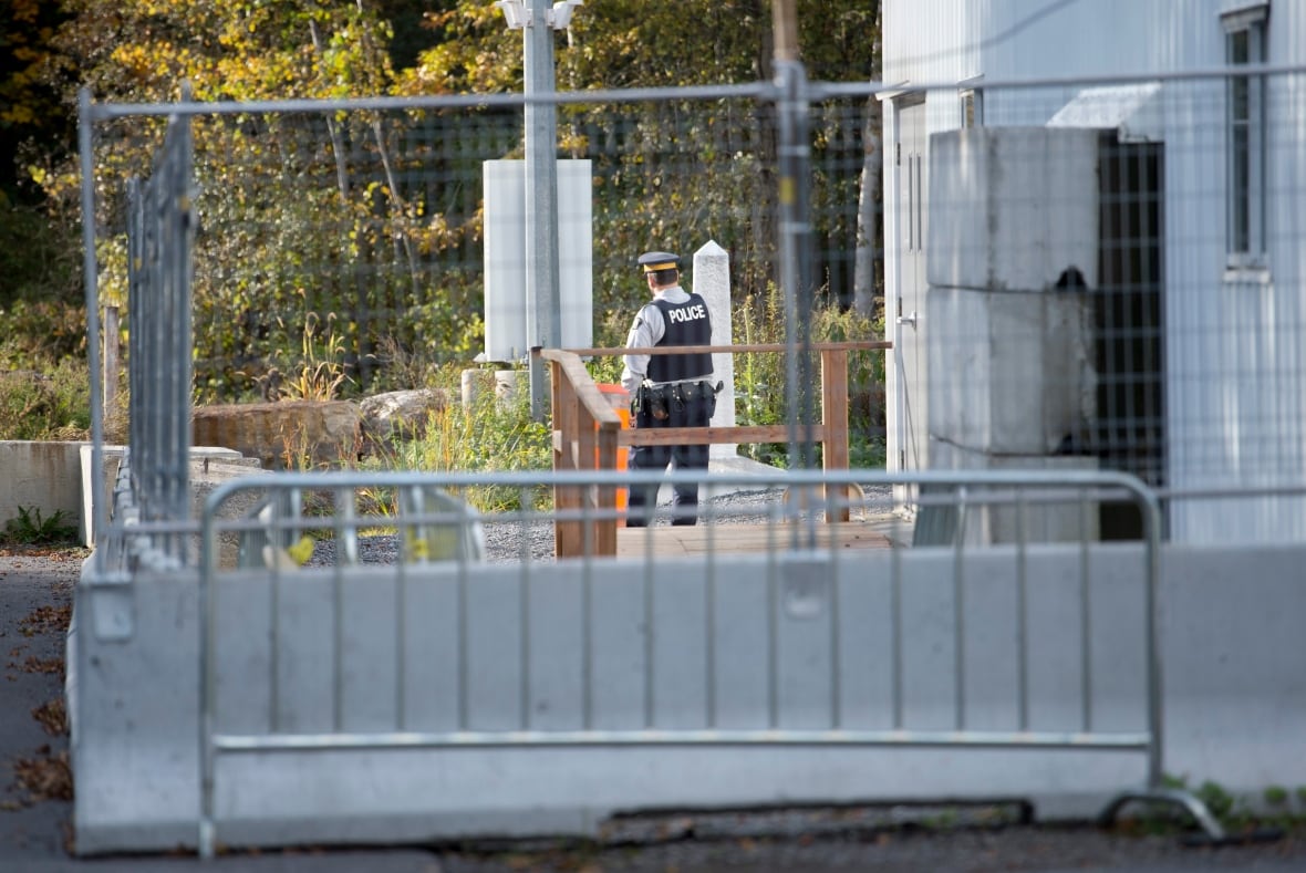 A police officer stands behind a gate at a former border crossing.