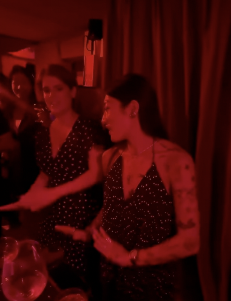 Princess Eugenie dancing in a red-hued room next to a woman